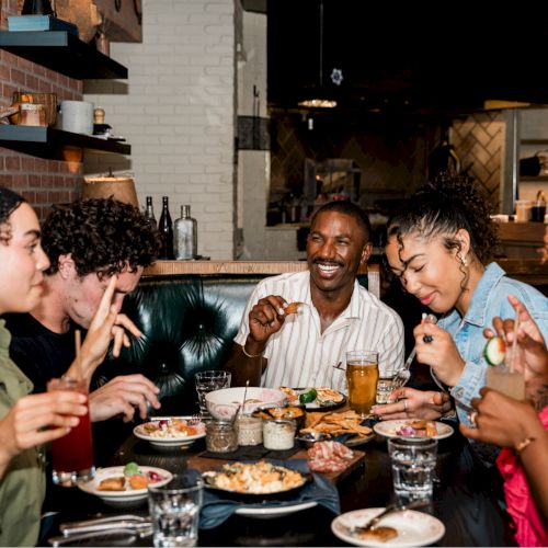 A group of people enjoying food and drinks at a cozy restaurant.