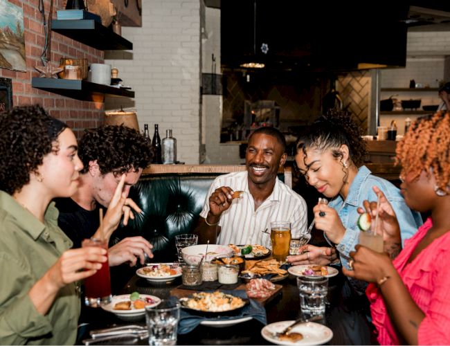 A group of people enjoying food and drinks at a cozy restaurant.
