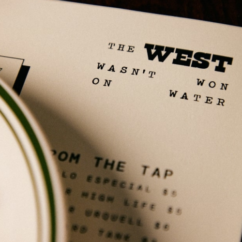 A plate partially covers a menu or sign displaying the text "The West wasn't won on water" with additional text visible at the bottom.