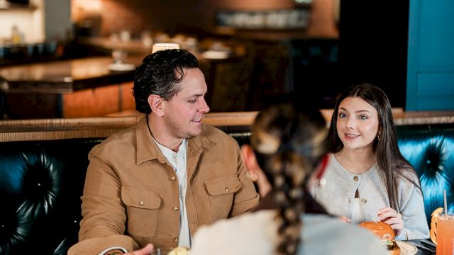 A group of friends chatting and laughing in a cozy restaurant booth, enjoying drinks and conversation.